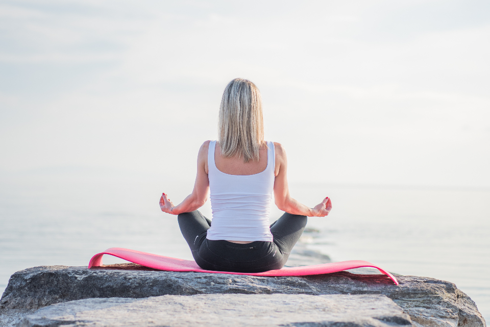 Person practising yoga by the water